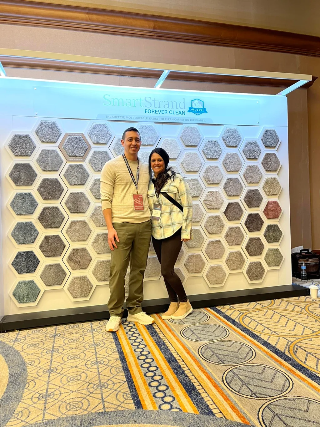 Best Flooring owners in front of a SmartStrand carpet sample display