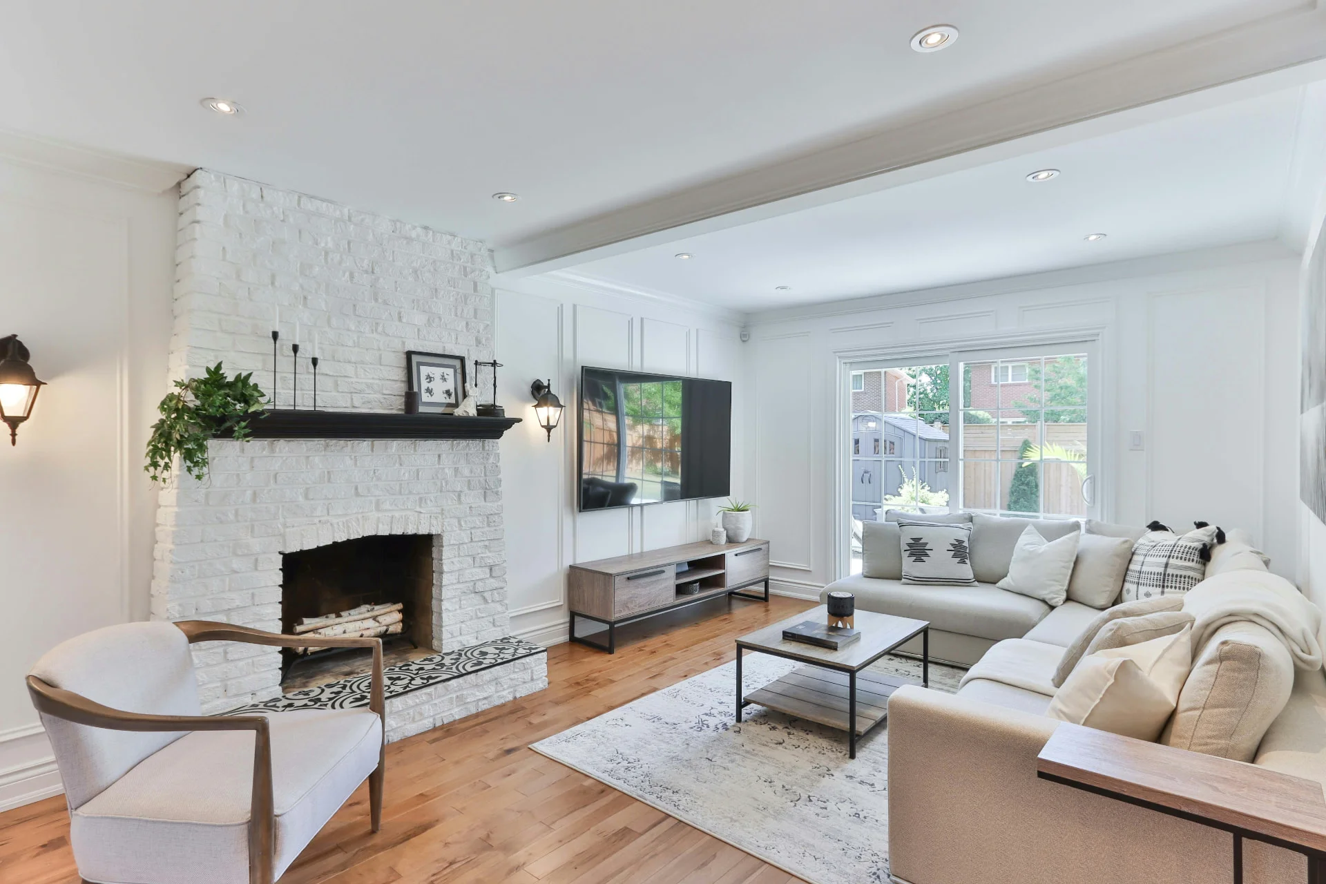 Bright living room with hardwood flooring, white painted brick fireplace, and modern furnishings